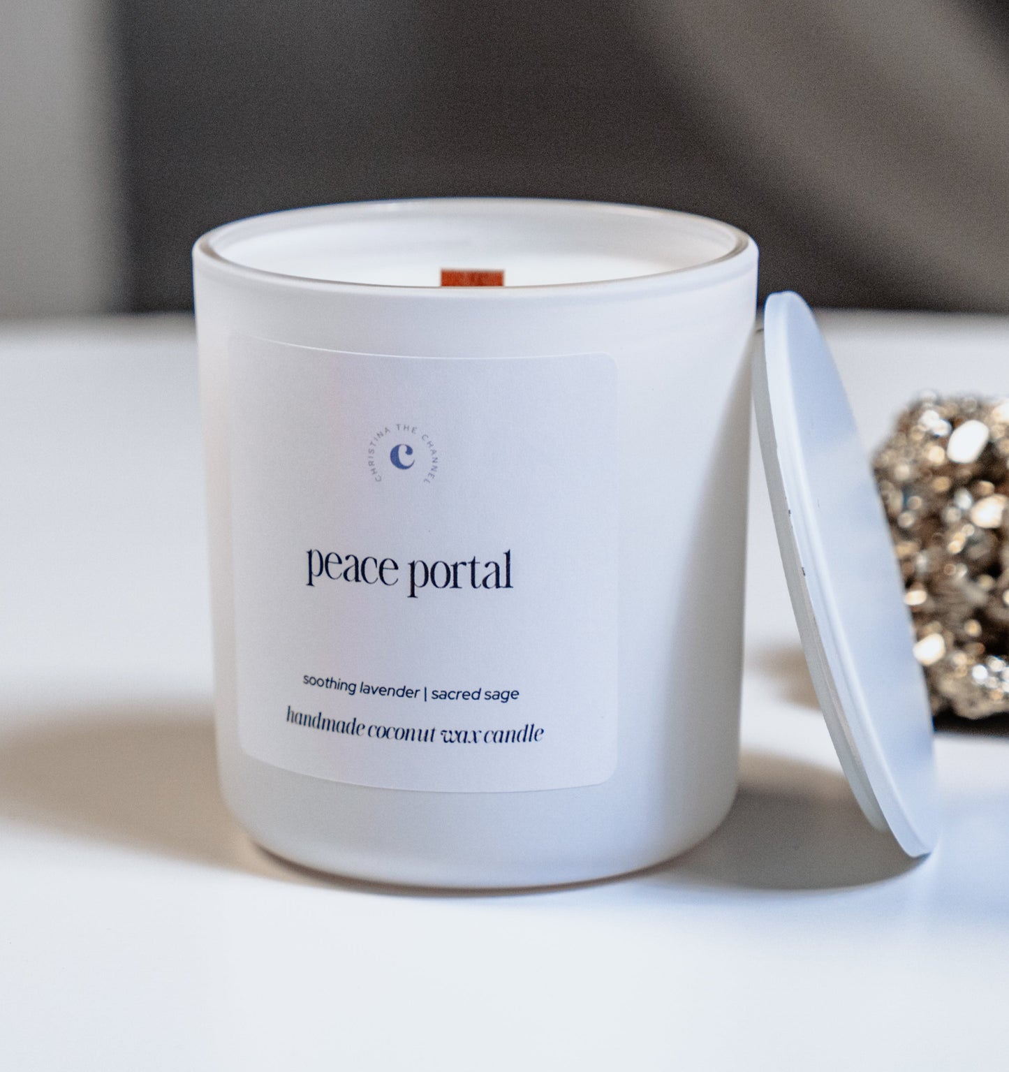 White candle labeled 'peace portal' on a white surface with a blurred background