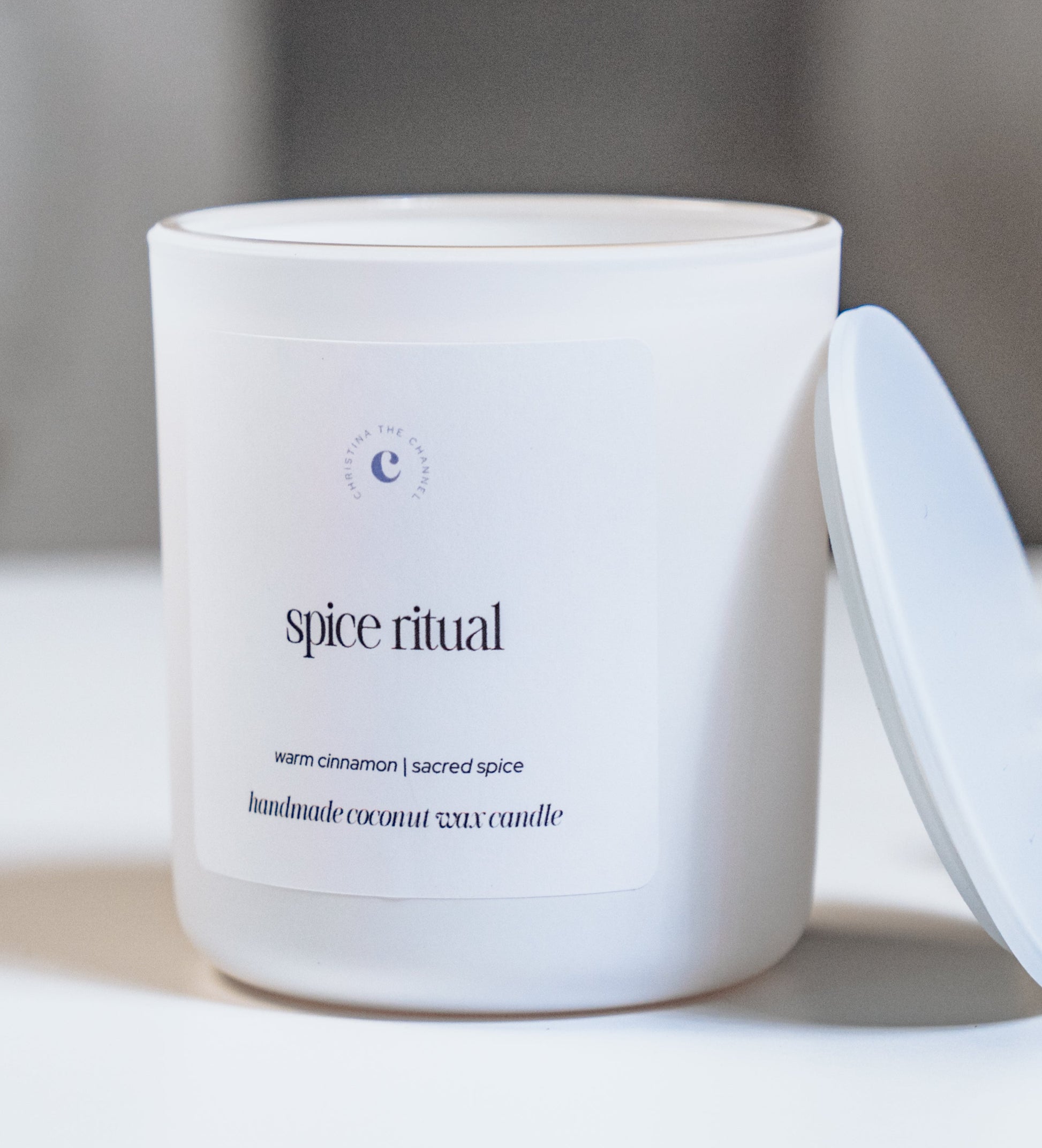 White candle labeled 'spice ritual' on a white surface with decorative elements.