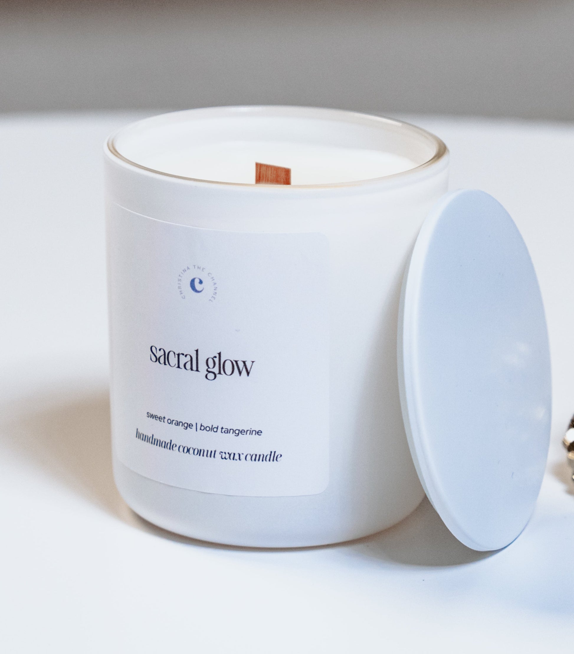 White candle labeled 'Sensual Glow' with a decorative rock on a white surface